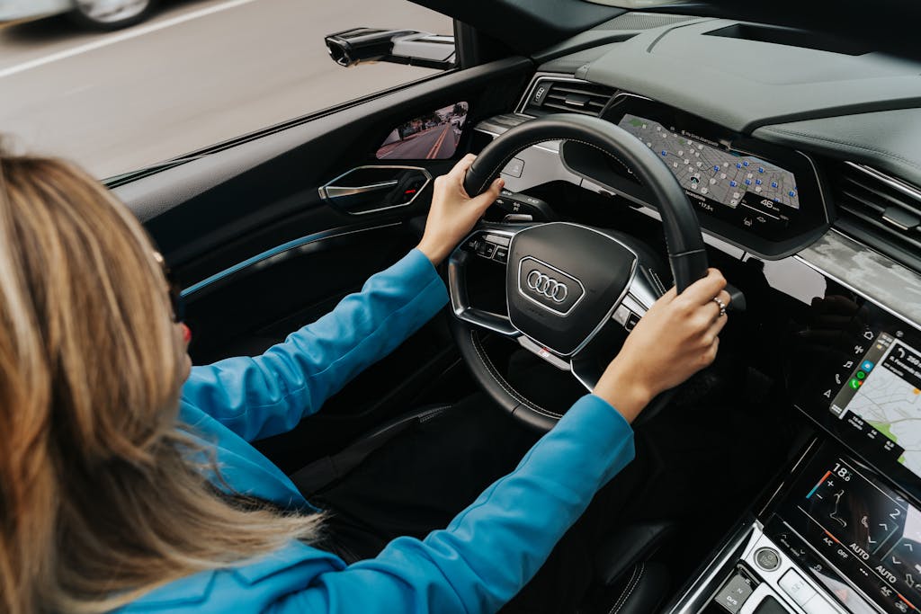 High angle view of a woman driving a modern Audi car, showcasing the dashboard and steering wheel.